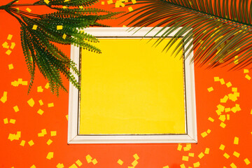 old retro frame with yellow copy space around it orange background with jungle leaves and yellow shredded papers, creative summer design