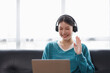 © David - Asian young female student sitting at the table, using laptop and headphones when studying.