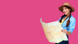 © khmelev - Smiling girl teen student in casual clothes and straw hat, backpack and digital camera holding map isolated on pink background. Female positive traveler. Caucasian tourist