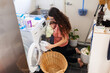 © Austockphoto - Young mum taking wet clean clothes out of washing machine while holding newborn baby