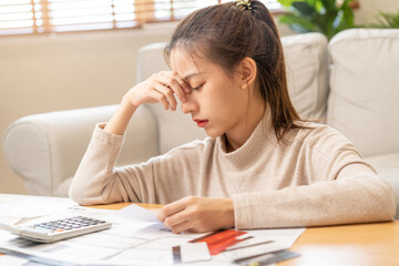 Wall Mural - Financial owe asian young woman, girl sitting suffer, stressed and confused by calculate expense from invoice or bill, have no money to pay, mortgage or loan. Debt, bankruptcy or bankruptcy concept.