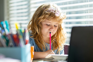 Fototapete - Child writing at school. Kid boy at home writes draws, classes for a child at home. Homeschool school boy doing homework and learning at class. Child hold a pencil and draw at home.