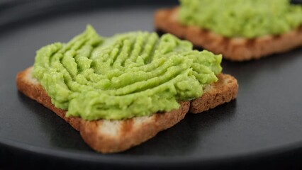 Wall Mural - Cooking avocado toast. Hands with fork spreading mashed avocado on toasted bread. Vegan food concept