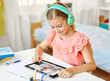 © Syda Productions - education, school and distant learning concept - happy student girl in headphones with tablet computer having online class at home
