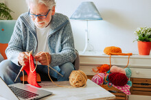 Senior Man At Home Follow Online Knit Tutorial To Relax And Enjoy Resting Home Leisure Activity Sitting On The Sofa - Male People Knitting With Computer Class Help - People Inner Lifestyle Hobby