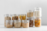 Fototapeta Kawa jest smaczna - food, culinary and storage concept - jars with different cereals, pasta, beans and cookies on white background