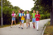 © Studio Romantic - School friendship. Funny schoolchildren group with backpacks have fun walking together on path in park. Cheerful boys and girls in summer casual clothes return home from school lessons together.