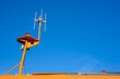 Communication mast on a bright orange Lifeboat or rescue boat against a clear blue sky.