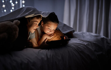 Poster - They stay entertained with technology. Shot of two adorable little siblings using a digital tablet together in bed at night.