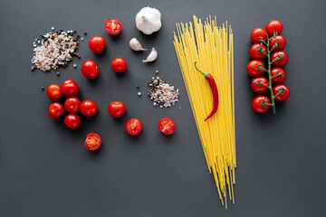 Wall Mural - Top view of fresh vegetables near aromatic spices and raw pasta on black surface.