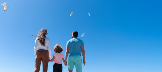 Wall Mural - Banner of family embracing on sea beach. Summer family vacation, horizontal banner. Holiday travel background. Parents with kid boy. Mom dad and son love relax together. Life insurance.