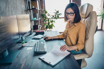 Poster - Portrait of attractive focused smart clever skilled girl leader partner reading documents developing at workplace workstation indoors