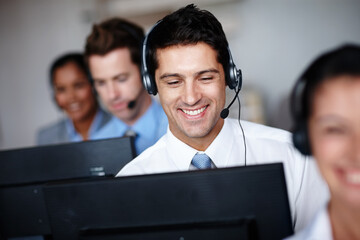 Pleased to assist you. A handsome young call center agent enjoying his job tremendously.