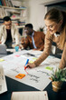 © Drazen - Happy creative woman drawing business plan on paperboard during meeting in office.