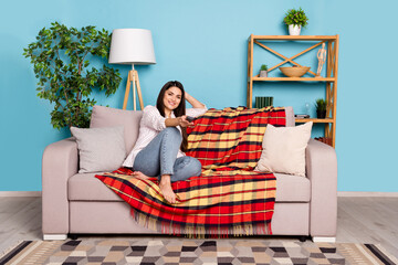 Sticker - Portrait of attractive cheerful girl sitting on divan staying alone watching film relax isolated on blue color background indoors