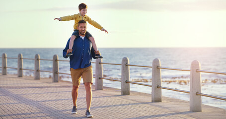 Canvas Print - Flying high in the sky. Shot of a cheerful father carrying his son on his shoulders while taking a walk on walkway near the beach.