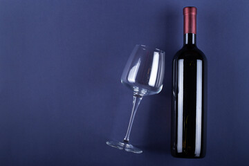 Wall Mural - Bottle of red wine without a label and a glass empty on a purple paper background. Mockup drink with place for you label and text. Space for text.