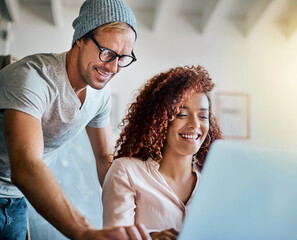Poster - We are going to change the world with this. Shot of two young cheerful businesspeople working together around a laptop in the office.