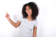 © Roquillo - Young beautiful girl with afro hairstyle wearing gray t-shirt over white background points aside on copy blank space. People promotion and advertising concept