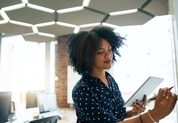 Poster - Her device is helping her plan. Shot of a young female designer working in her office.