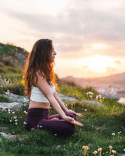 Young Woman Sitting In Lotus Pose And Meditating In Nature