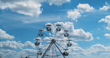 Small Ferris Wheel Against A Perfect Blue Sky With White Clouds. Slow Rotation, Calm Rest