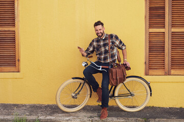 Poster - I get around. Portrait of a young man using his cellphone while standing outside with his bicycle.