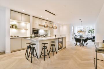 white cabinets with wooden counter of modern kitchen and dining table set in living room of apartmen