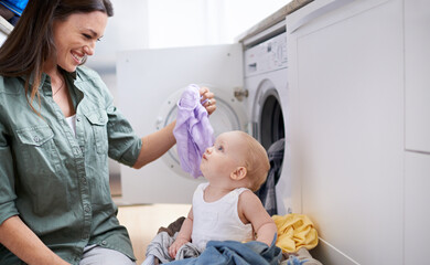 Canvas Print - Mommys little helper. Shot of a mother and her baby girl playing while doing laundry.