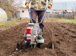 A man works the land in the garden with a cultivator, prepares the soil for sowing. farming concept