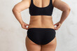 © Юля Бурмистрова - Cropped rearview of fat, adipose, overweight female body in black underwear, checking and holding excess folds, sides on back. Cellulite friable skin problem. Dieting and unhealthy eating problem
