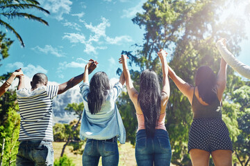 Together we rise. Rearview shot of a group of young friends raising their hands in triumph.