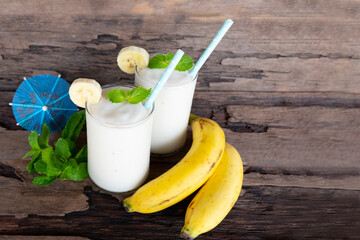 Banana fresh cocktail vanilla smoothies  fruit juice beverage healthy the taste yummy in glass drink episode good morning on wooden background from the top view.