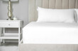 Mattress with white fitted sheet and pillows indoors