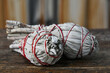 A close up image of two white sage smudge sticks wrapped with bright red thread. 