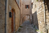 Fototapeta Uliczki - narrow medieval street with brick walls and arched doors and windows