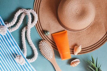 Wall Mural - Flat lay summer travel photography. Striped bag, straw hat, orange sunscreen tube, wooden hair brush and seashells. Beach essentials, vacation packing