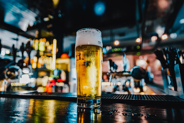 Wall Mural - glass of light beer stand on bar counter in a bar or pub