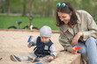 © Vladimir Sazonov - Mother and son in sandbox at playground.