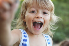 Close-up Of A Blond Boy In The Sand Happily Screaming