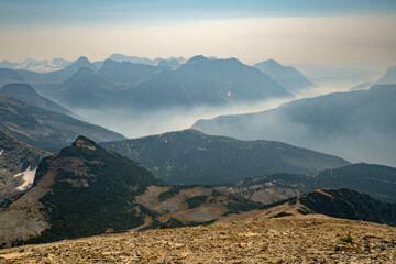 Wall Mural - Wildfire smoke fills up valley in vast mountains of Glacier National Park, Montana, USA on a hot dry day of summer. Climate change impact. Global warming.