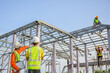 © เลิศลักษณ์ ทิพชัย - A team of male engineers working at a house construction site. Discuss with the workers and plan the construction of the steel roof truss.