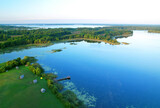 Fototapeta Do pokoju - Lake in wild nature, aerial view. Lake on sunset in summer. Aerial panoramic landscape view of lake in wildlife. Drone view of wetland in green colors. Rural environment, clean air and ecology. Pond.