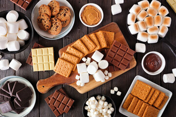 Wall Mural - Smores buffet table scene. Roasted marshmallows, crackers, chocolate and an assortment of ingredients. Top down view over a dark wood background.