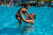© Юля Бурмистрова - Grandmother and granddaughter in the pool. A young grandmother throws a girl in an inflatable circle over the surface of the water in the hotel pool on a summer vacation.