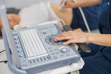 Wall Mural - Close up of doctors ultrasound hands examine patient abdomen at hospital. Prenatal diagnosis center