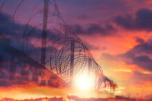 Country Border Protection. A Metal Fence With Barbed Wire Under Tension. Cloudy Twilight Sky On The Background. Double Exposure. The Concept Of Immigration, Prison And Hope