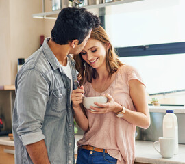 Wall Mural - Enjoying the food...and the kisses. Shot of an affectionate young couple standing in their kitchen.