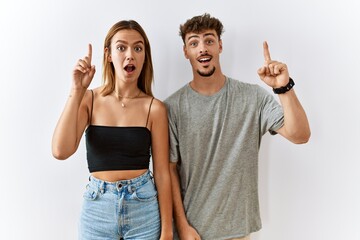 Wall Mural - Young beautiful couple standing together over isolated background pointing finger up with successful idea. exited and happy. number one.