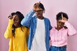 Group of three young black people standing together over pink background making fun of people with fingers on forehead doing loser gesture mocking and insulting.